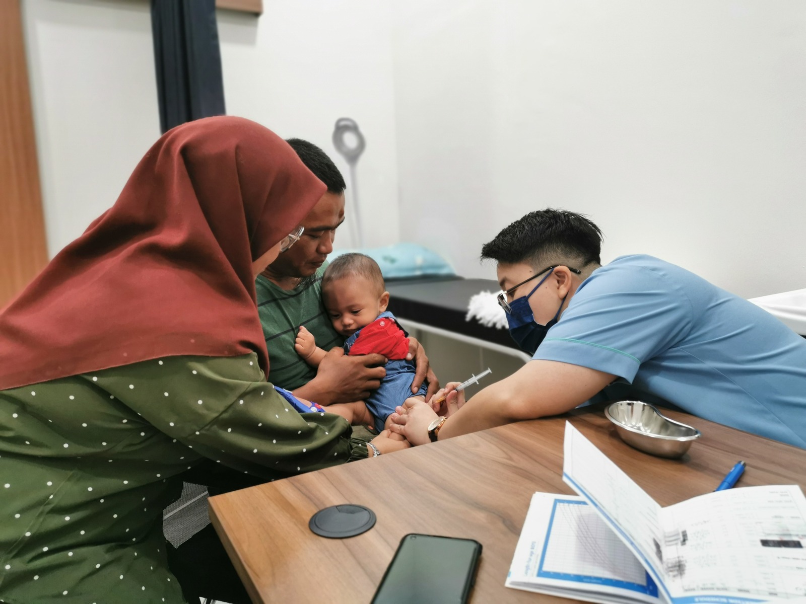 Baby receiving a vaccination with parents at Klinik Tong & Surgeri