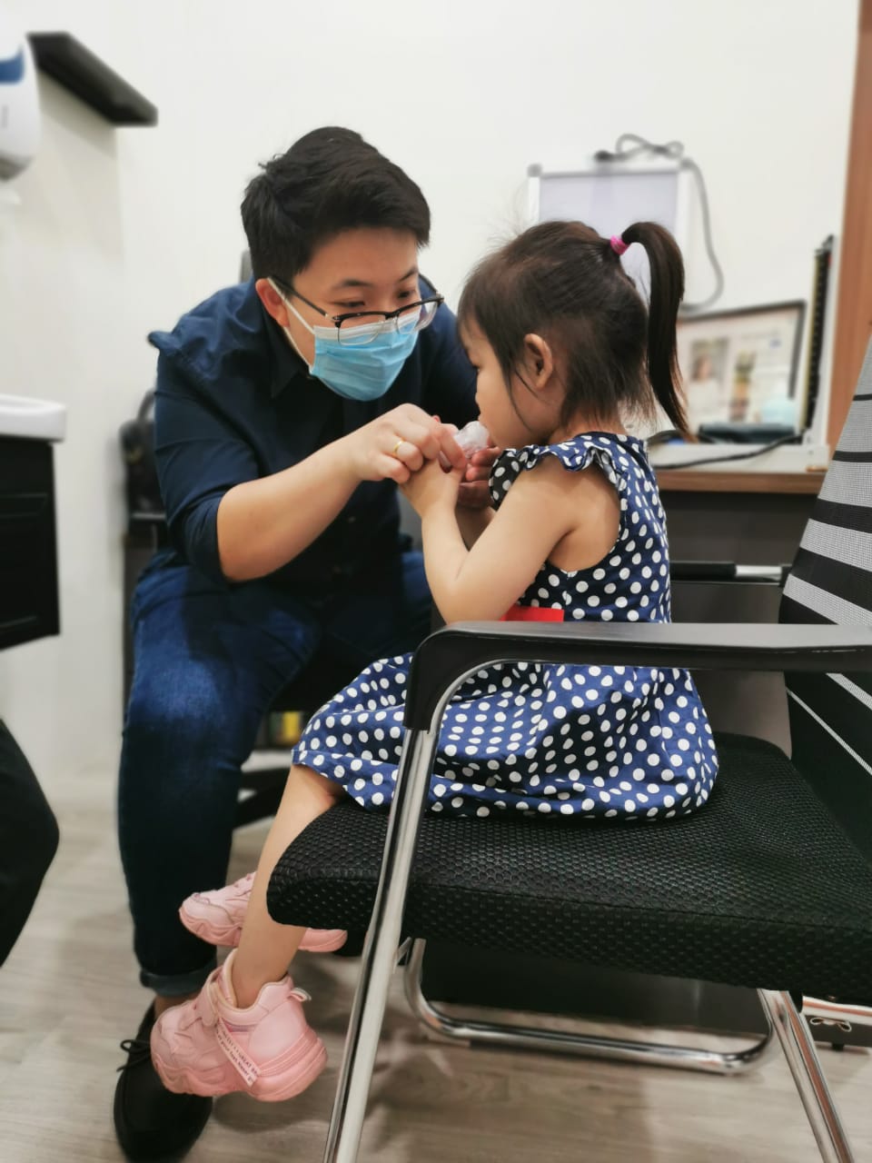 Doctor teaching a child correct inhaler technique during paediatric care at the clinic