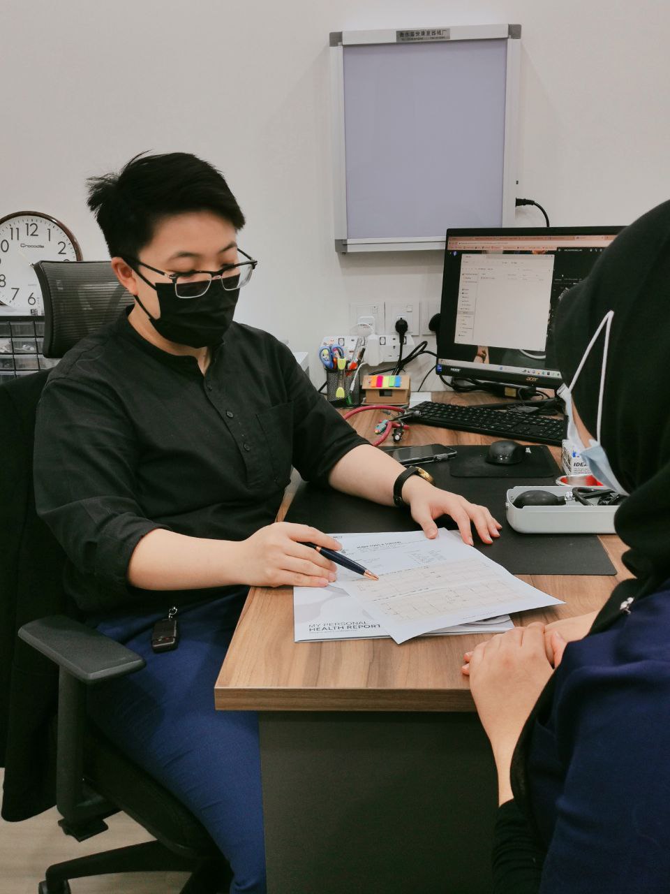 Doctor reviewing a personal health report with a patient at Klinik Tong & Surgeri